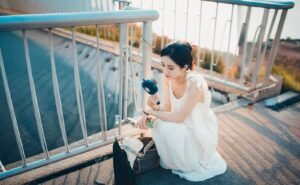 Woman cooling down with a portable handheld fan outdoors on a sunny summer day