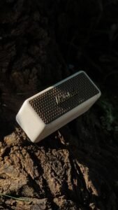 Portable Bluetooth speaker resting on tree bark outdoors